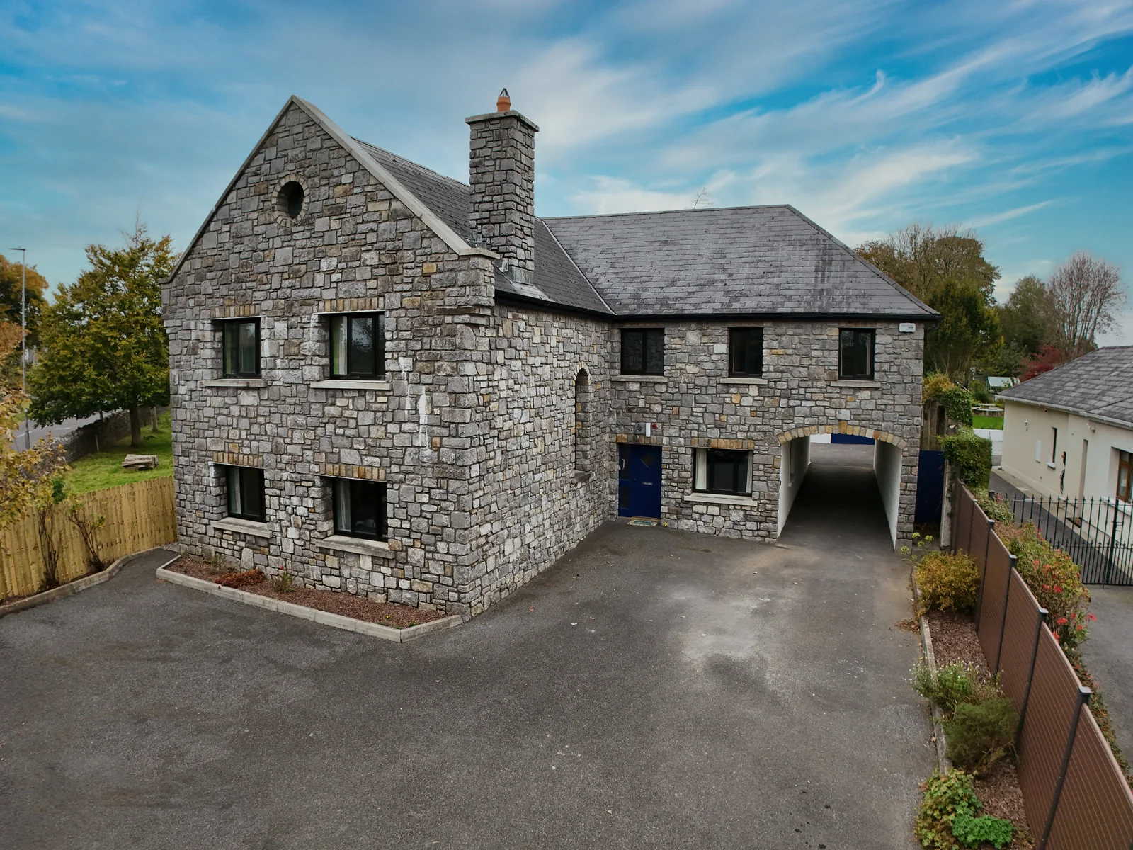 A stone-built home with its driveway and entrance archway